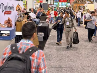 Pasillo principal del piso de exhibición de IFPA 2025 con asistentes de todo el mundo